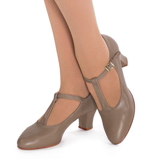 On‑foot view of tan ladies T‑strap concert shoe worn with tan stockings, showing secure T‑strap fit, mid‑height heel, and elegant silhouette for performance.